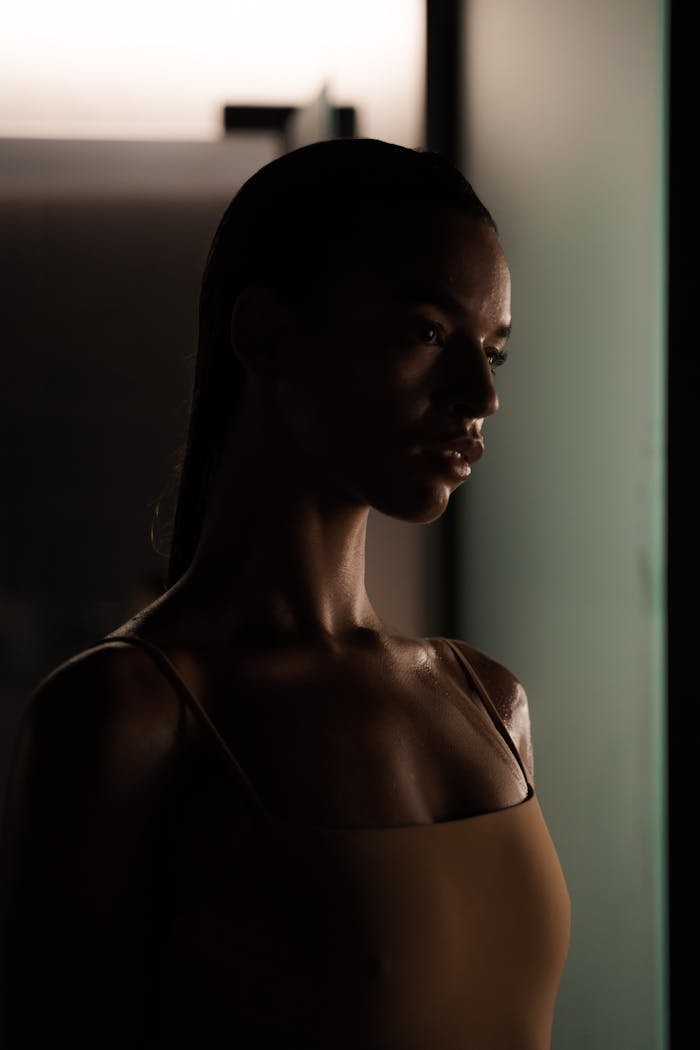 Artistic portrait of a young woman in a dimly lit spa environment, emphasizing relaxation and luxury.